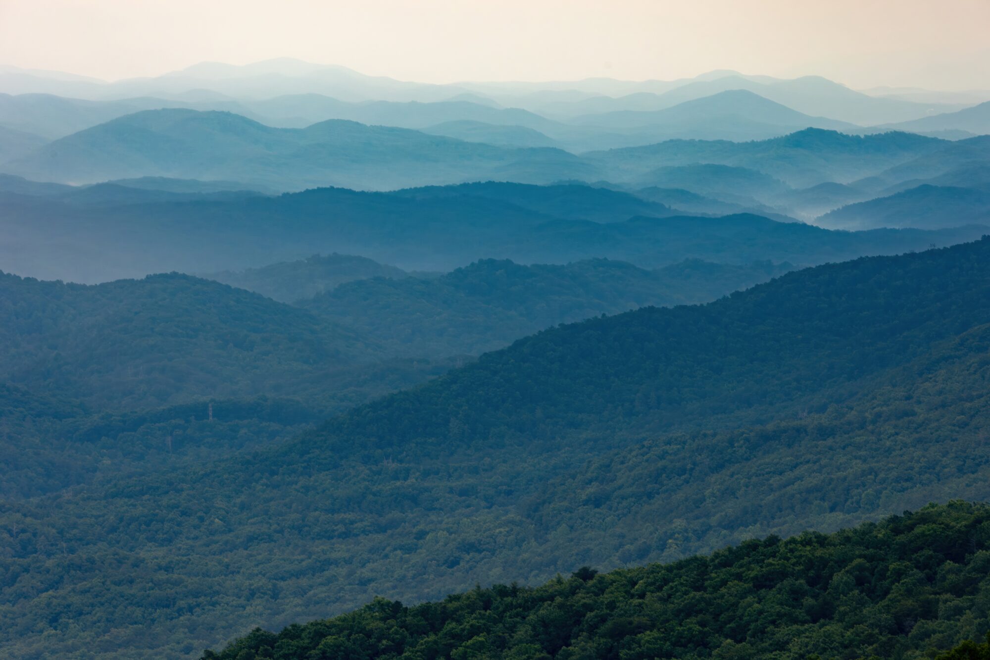 Layers of forested mountain ridges fade from green to pale blue into the hazy distance, seen from Look Rock Tower on the Foothills Parkway, Great Smoky Mountains, Tennessee.